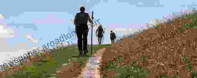 A Photograph Of A Pilgrim Walking Along A Desolate Path With Rolling Hills In The Distance. Walking West On The Camino Encore Une Fois